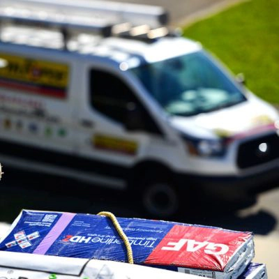 bundle of GAF shingles with a StormForce Roofing van in the background
